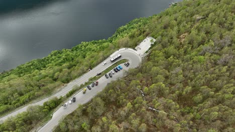 Busy-viewpoint-full-of-cars-and-tourists-at-Ornesvingen-in-Eagles-road-Geiranger---Descending-aerial-looking-down-at-busy-viewpoint---Norway