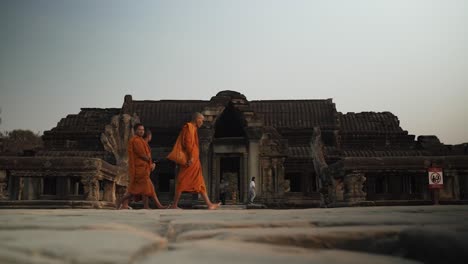 Buddhist-Monks-walking-past-an-Ancient-Temple-at-Angkor-Wat---Siem-Reap,-Cambodia