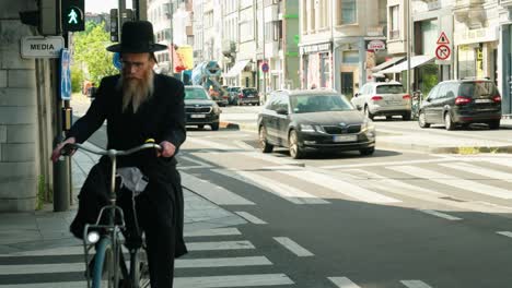 Judío-Ortodoxo-En-Bicicleta-En-El-Distrito-De-Los-Diamantes-De-Amberes-Y-Espera-Hasta-Que-Pueda-Cruzar-La-Calle-De-La-Ciudad---Bélgica