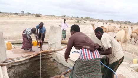 Afrika,-Kenia,-Kenianisch-somalische-Grenze-–-Eine-Gruppe-Junger-Kenianer-Holt-Wasser-Aus-Einem-Der-Brunnen,-Um-Kamele-In-Einem-Armen-Dorf-An-Der-Grenze-Zwischen-Kenia-Und-Somalia-Zu-Trinken-–-20.-August-2018