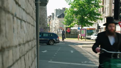 Orthodox-Jewish-man-biking-in-the-Antwerp's-diamond-district-on-a-sunny-day,-Belgium
