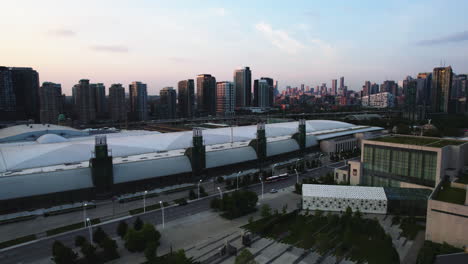 Aerial-view-rising-over-the-Enercare-Centre-toward-the-central-Toronto-skyline,-sunrise-in-Canada