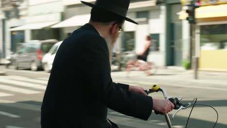 Judío-Ortodoxo-Esperando-En-Bicicleta-En-La-Intersección-Y-Cruzando-La-Calle-De-La-Ciudad-En-El-Distrito-De-Los-Diamantes-De-Amberes,-Bélgica---Cerrar