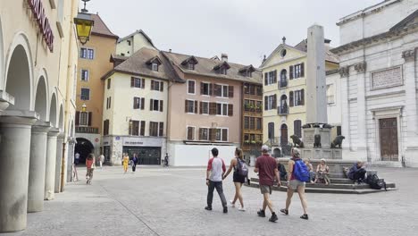 Place-Notre-Dame-square-in-Annecy-one-of-the-bus-see-points-if-visiting,-with-group-of-tourists-passing-by