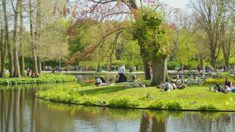 Gente-Relajándose-Junto-Al-Agua-En-Vondelpark,-Amsterdam-En-Un-Día-Soleado