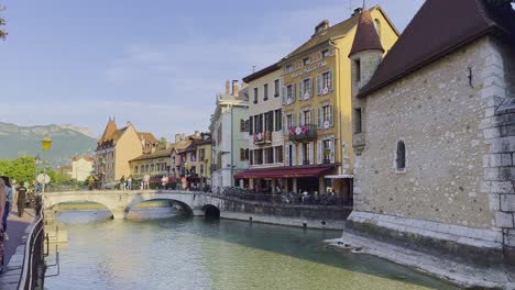 Afternoon-sun-on-bridge-warming-the-facade-of-the-old-Annecy-with-the-view-over-stone-bridge,-canal-and-medieval-houses