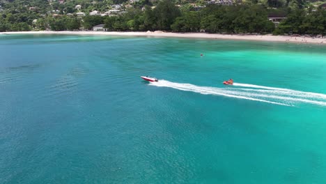 Tourist-couple-having-a-donut-ride-at-the-Watersport-at-the-beau-vallon-beach,-beautiful-sunny-day-and-calm-sea,-Mahe-Seychelles-1