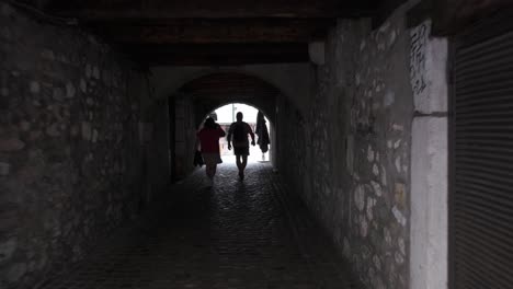Gente-Caminando-Por-Un-Pasillo-Oscuro-Y-Arqueado-Cerca-De-La-Orilla-Del-Río-En-Annecy,-Francia