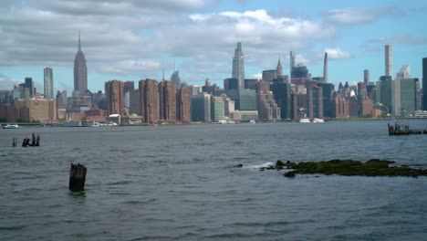 Manhattan-Skyline-Von-Brooklyn,-East-River-Mit-Wellen-Im-Vordergrund,-Mit-Blick-Auf-Das-Empire-State-Building,-One-Vanderbilt-Und-Midtown-Manhattan