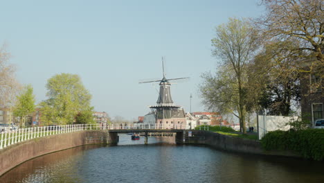 Molino-De-Viento-Histórico-Iluminado-Por-El-Sol-Junto-Al-Agua-En-Haarlem,-Países-Bajos