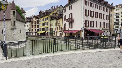 Busy-pedestrian-bridge-in-Annecy-with-tourists-stopping-to-photograph-scenery