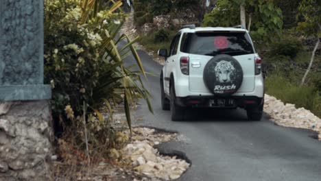 Toma-Manual-En-Cámara-Lenta-De-Automóviles-Y-Scooters-En-Movimiento-En-La-Isla-De-Nusa-Penida-En-Bali,-Indonesia,-Conduciendo-Por-Carreteras-Estrechas