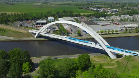Aerial-Orbit-of-Modern-White-Arch-Train-Bridge:-Bert-Swart,-Arriva-Train-Driving-Past