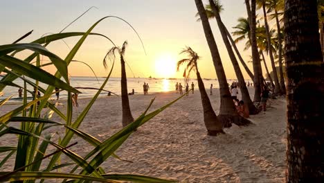 Menschen-Genießen-Den-Wunderschönen-Sonnenuntergang,-Der-Den-Himmel-Am-Strand-Der-Insel-Boracay,-Philippinen,-Gelb-Färbt