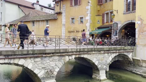 Turistas,-Peatones-En-Un-Puente-De-Piedra-En-Annecy-Con-Una-Hermosa-Arquitectura.