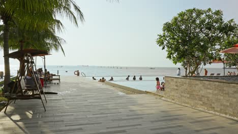 Hermosa-Playa-En-El-Resort-Con-Muchos-Turistas-Disfrutando-De-La-Piscina-Durante-Sus-Vacaciones