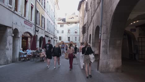 People-walking-and-talking-on-the-street-in-Annecy,-France-an-old-quarter-with-arched-passageway