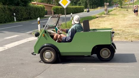 Couple-sitting-in-traditional-mini-vintage-cabriolet-car-on-road-during-sunny-day-in-germany---Slow-motion-static