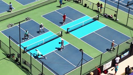 High-angle-view-above-people-playing-on-blue-pickleball-courts-at-Valencia-tournament,-Close-up-aerial-overhead