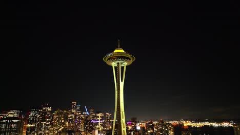 Cinematic-establishing-view-looking-up-at-the-Space-Needle,-aerial-at-night-in-Seattle-with-city-lights