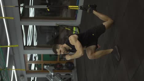 Sportsman-doing-squats-exercises-with-TRX-straps-at-gym