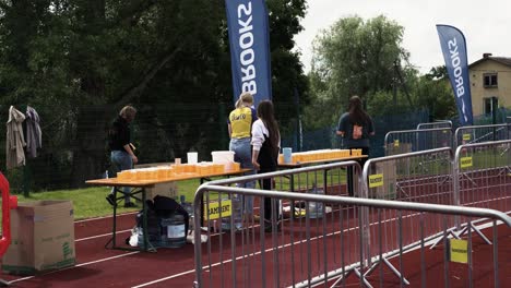 Triathlon-stewardess-offering-cold-beverage-to-passing-track-runners-at-check-point