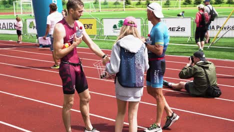 Young-stewardess-offering-triathlon-runners-snacks-at-athletic-endurance-event-finish-line