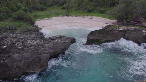 Reveal-shot-of-Pantai-Mandorak-Sumba-Island-with-rough-sea-at-sunrise,-aerial