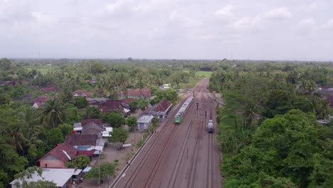 Small-green-train-driving-through-green-scenery-at-java-Indonesia,-aerial