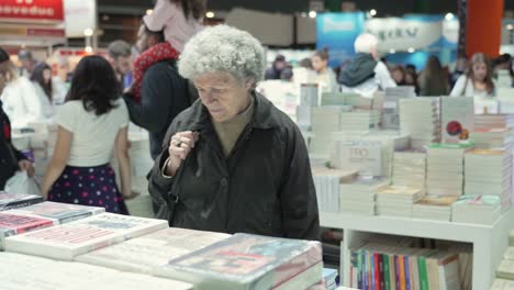 Una-Anciana-Pasa-Y-Hojea-Mirando-Montones-De-Libros-En-La-Feria.