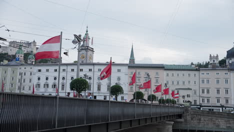 Ein-Blick-Auf-Eine-Brücke,-Auf-Der-Am-Nachmittag-Menschen-In-Salzburg,-Österreich,-Spazieren-Gehen,-Mit-Einem-Gebäude-Im-Hintergrund-Und-Einem-Klaren-Himmel-An-Der-Spitze