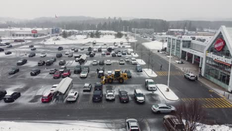 Luftaufnahme-Eines-Katzenschneeschiebers,-Der-Winterschnee-Auf-Dem-Parkplatz-Eines-Einkaufszentrums-Räumt