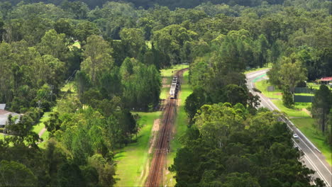 Queensland-Train-Railway-Traveling-Through-Rural-Countryside-Suburb,-4K-Drone-Telephoto-Australia
