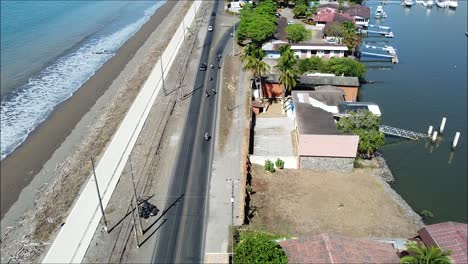 many-motorcycles-and-car-on-the-road-by-the-sea,-costa-rica,-puntarenas,-pura-vida,-long-street,-beach,-port