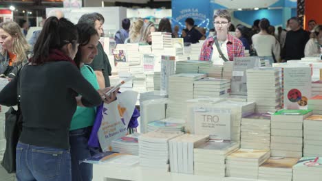 Two-girls-thumb-through-and-read-preview-back-cover-of-new-book-at-fair