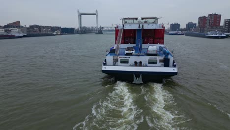 Stern-View-Of-Belicha-Inland-Freighter-Transporting-Intermodal-Containers-Along-Oude-Maas-With-View-Of-Spoorbrug-Railway-Bridge-In-background