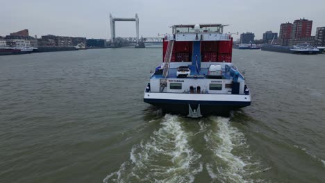 Heckansicht-Des-Binnenfrachters-Belicha,-Der-Intermodale-Container-Entlang-Der-Oude-Maas-Transportiert,-Mit-Blick-Auf-Die-Eisenbahnbrücke-Spoorbrug-Im-Hintergrund