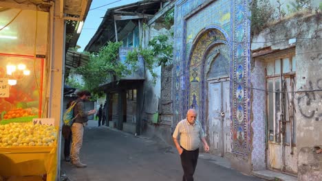 Anciano-Persa-Caminando-Por-Una-Pasarela-En-El-Casco-Antiguo-De-La-Ciudad-Frente-A-Una-Antigua-Y-Colorida-Puerta-Histórica-Con-Azulejos-Azules,-Pared-De-Fama-De-Amor-En-El-Centro-De-La-Ciudad-En-Un-Mercado-De-Agricultores-Locales