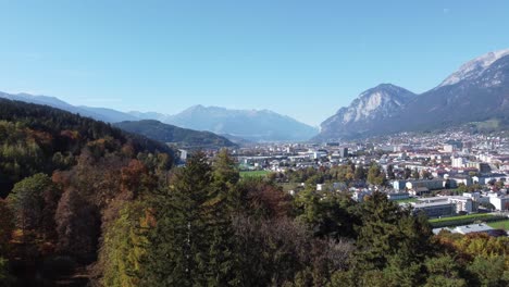 Innsbruck-in-aerial-view-approaching-from-a-hill-with-ancient-alpine-forests-in-the-background-the-alps-in-Tyrol-in-Austria