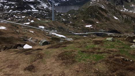 Aerial-drone-tilt-up-forward-view-of-wind-turbine-and-dam-in-background-at-Gotthard-pass-in-Switzerland