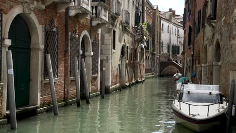 A-speed-boat-moored-in-a-small-canal-waterway-surrounded-by-beautiful-buildings-in-Venice,-Italy