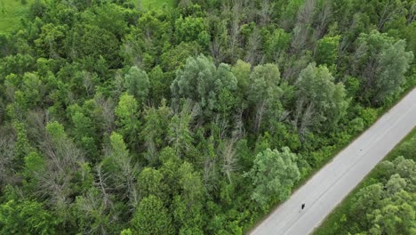 Man-Running-On-A-Road-Through-The-Forest---aerial-drone-shot