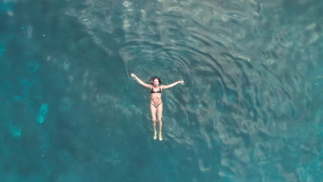 Aerial-static-shot-of-woman-swimming-in-the-sea