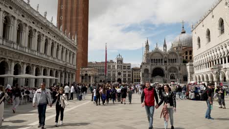 Un-Día-Ajetreado-En-La-Plaza-San-Marco-Mientras-La-Gente-Camina-Por-La-Plaza-Rodeada-De-Los-Hermosos-Edificios-Y-La-Arquitectura-De-La-Ciudad-Histórica,-Venecia,-Italia