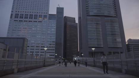 Blick-Am-Frühen-Abend-Auf-Den-Gehweg,-Der-Zu-Bürogebäuden-In-Shinjuku-Führt,-Mit-Menschen,-Die-In-Tokio-Entlanggehen