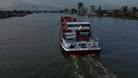 Vista-De-Popa-Del-Carguero-Interior-De-Aquapolis-Que-Transporta-Contenedores-Intermodales-A-Lo-Largo-De-Oude-Maas-Con-Vista-Al-Puente-Ferroviario-De-Spoorbrug-En-Segundo-Plano