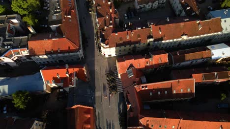 Aerial-shot-of-historic-houses-and-narrow-streets-in-Kaunas-old-town-by-a-Nemunas-river-in-Lithuania-on-a-sunny-evening,-top-down-shot