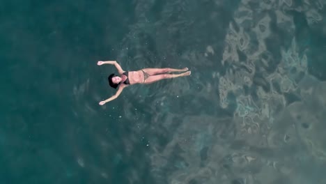 Aerial-drone-pull-out-of-woman-swimming-in-the-ocean