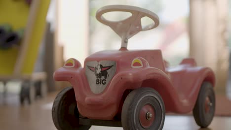 Handheld-shot-of-red-BIG-bobby-car-with-white-steering-wheel-in-a-kindergarten