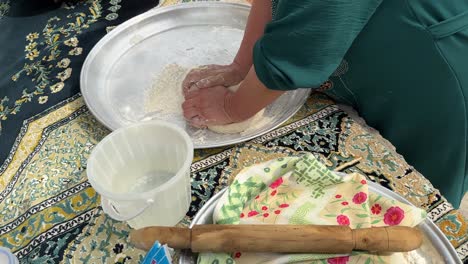 Rubbing-pushing-and-prepare-bread-flour-dough-kneading-in-a-metal-plate-to-make-fermentation-in-rural-life-to-make-flat-bread-fresh-smoky-food-in-tube-fire-wood-oven-by-Persian-woman-mother-Gilan